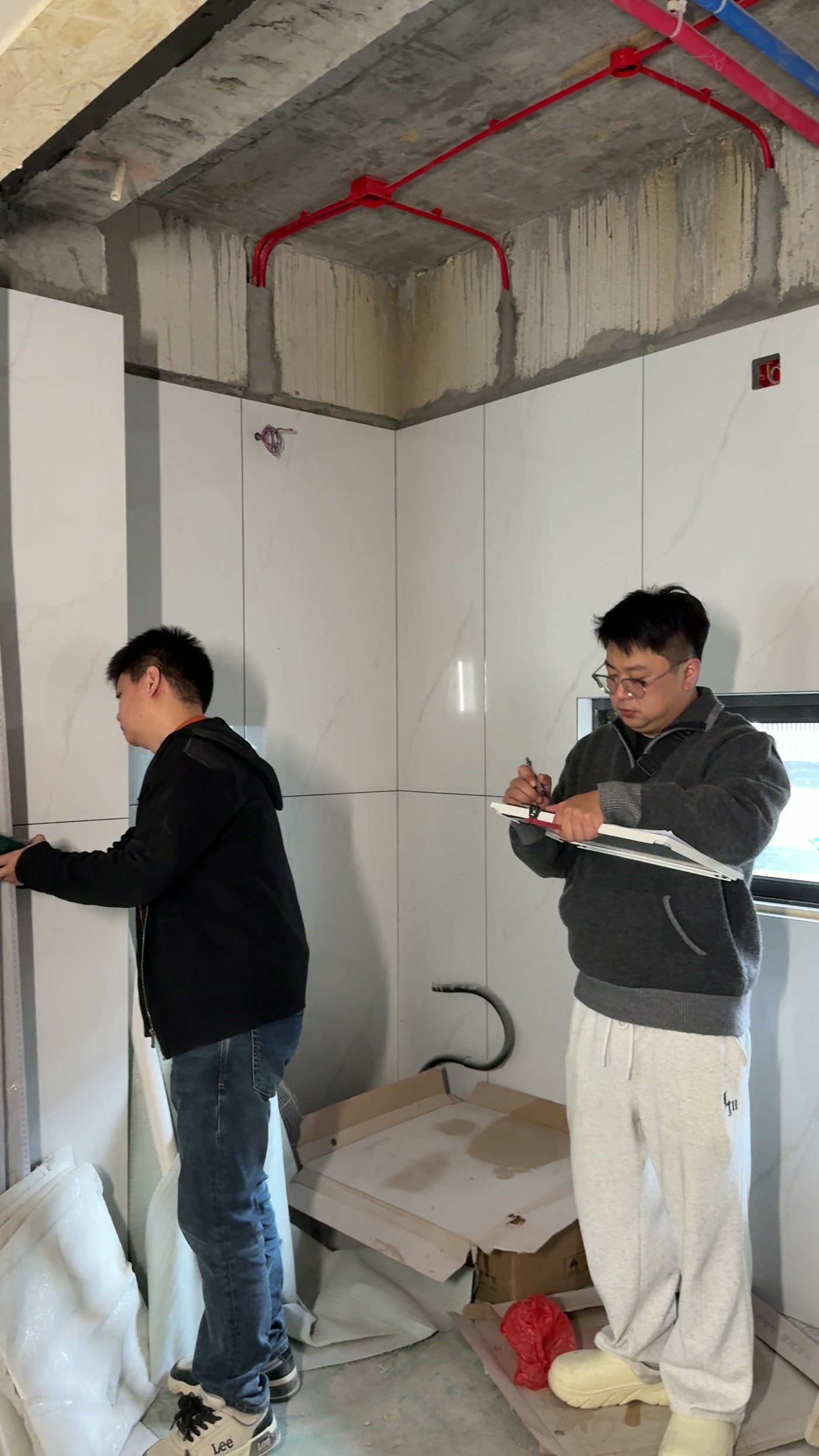 两个人在工地现场对尺寸、做记录